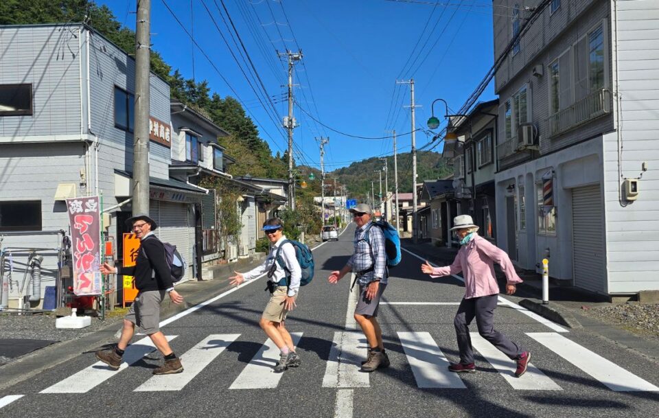 Four hikers on a pedestrian crossing in a town on the Michinoku Coastal Trail