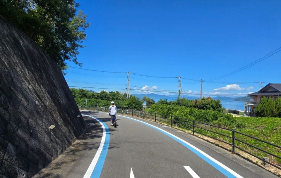 Cycling through a rural town on the Shimanami Kaido on a sunny day with views of the islands in the Seto Inland Sea