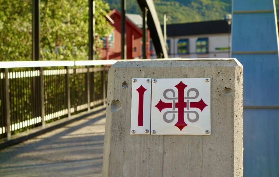 Stone waymarker with the red & white cross, symbol of St Olav's Way pilgrimage in Norway.