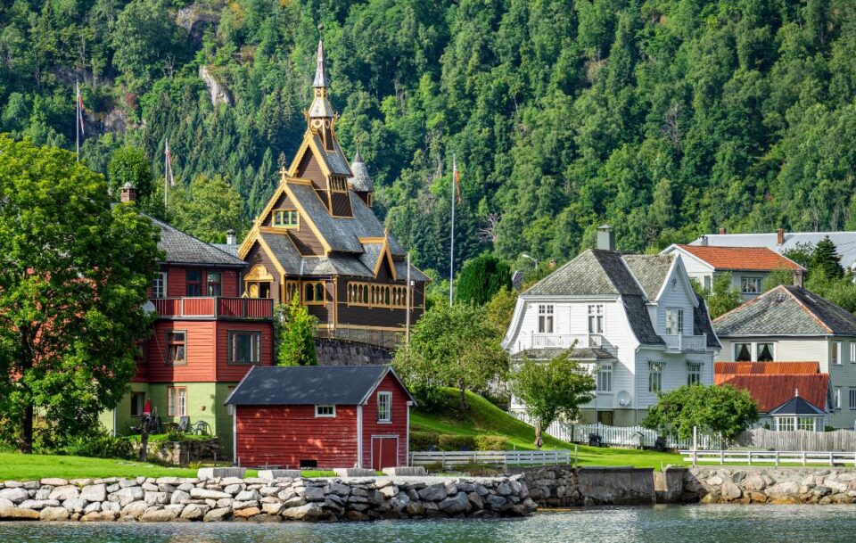 Traditional houses and church alongside a river on St Olav's Way in Norway