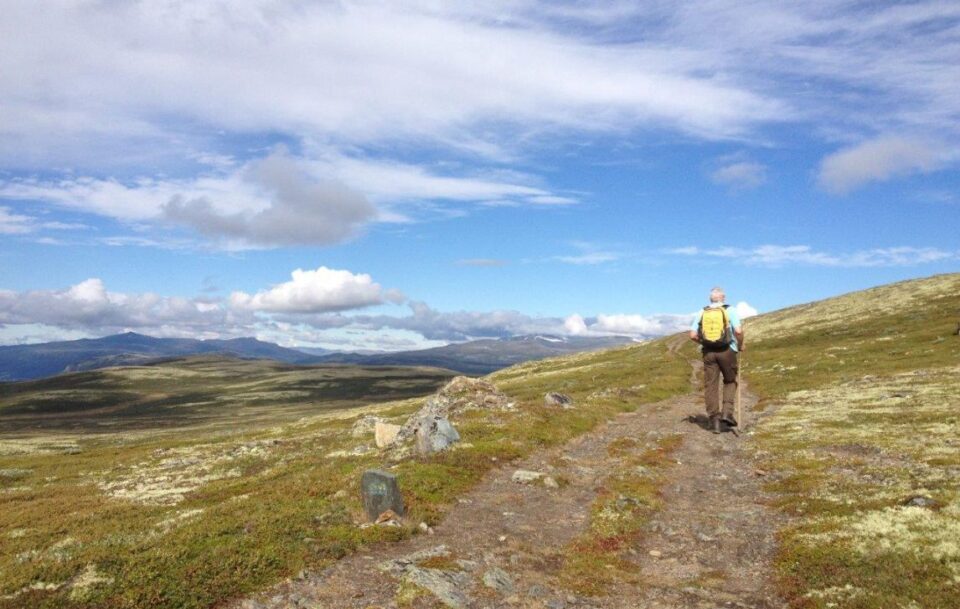 Solo male hiker walking on a stony path across a barren landscape on St Olav's Way in Norway