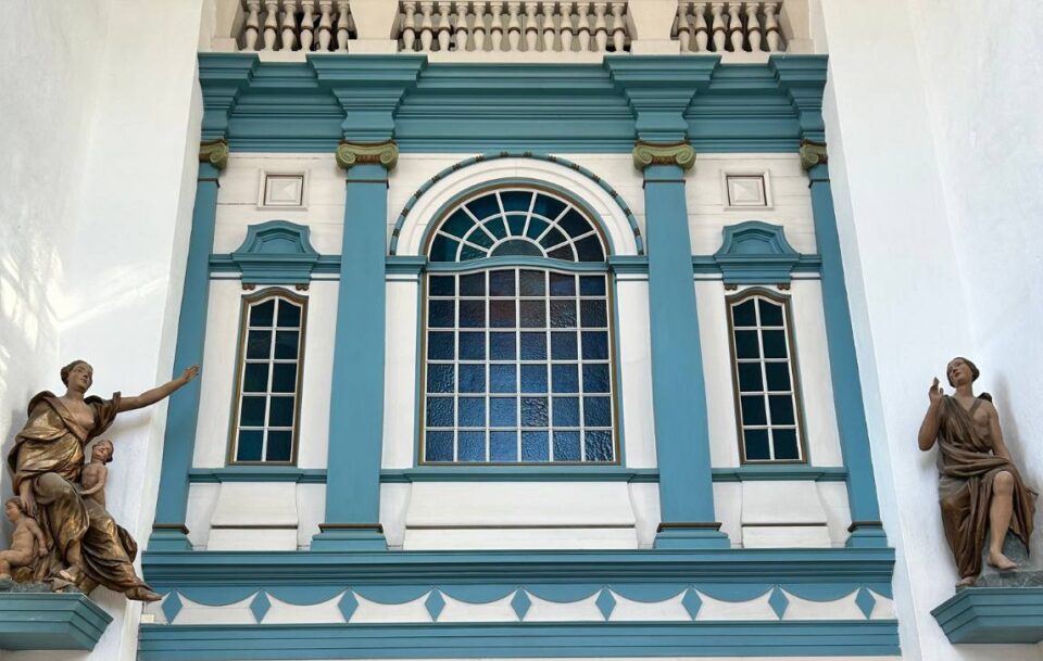 Building exterior with arched window and gold female statues, Trondheim, Norway.