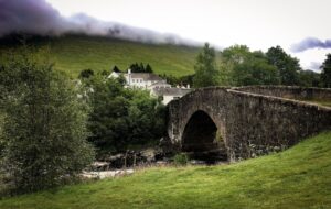 Stone bridge and white farmhouse on the West Highland Way in Scotland.