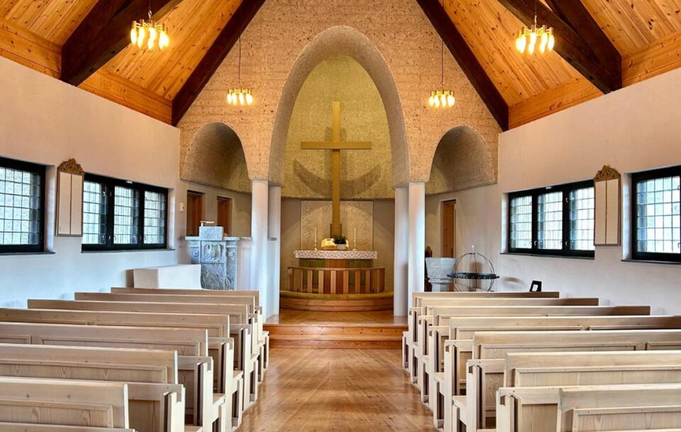 Interior of a small church on St Olav's Way with a beautiful ceiling and cross at the altar.