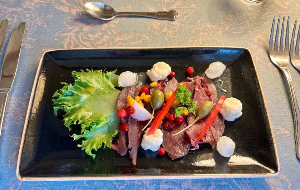 Delicious fresh salad and rare-cooked red meat served on a rectangular plate, St Olav's Way, Norway.
