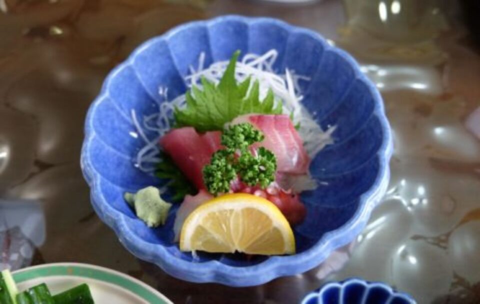 Close up of Japanese sashimi in a blue bowl.