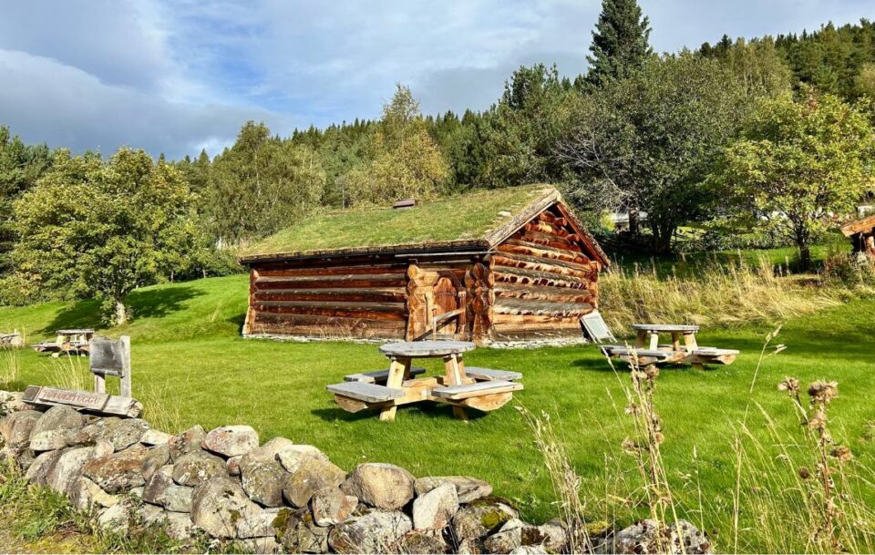 Traditional turf-roofed hut and wooden picnic tables along St Olav’s Way.