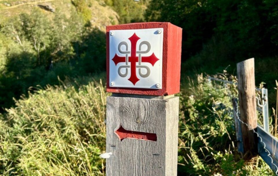 Traditional wooden marker with the red St Olav’s cross along the St Olav's Way pilgrimage route in Norway.