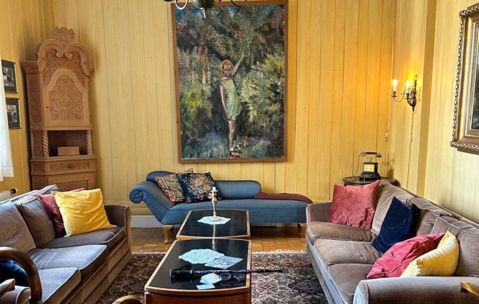 Comfy hotel lounge room featuring yellow walls and vintage furnishings, along the St Olav’s Way pilgrim route.