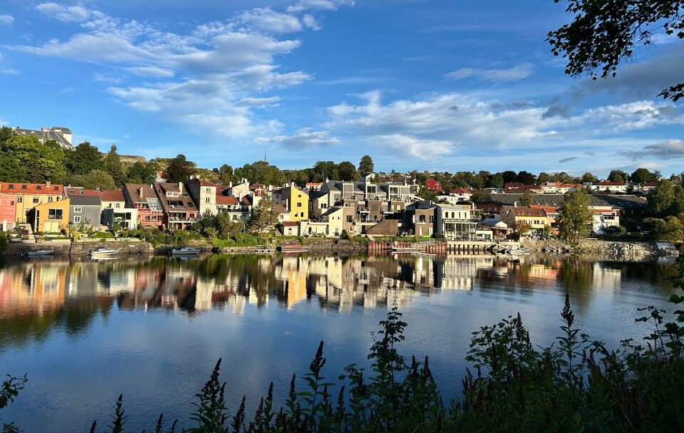 Scenic view of Trondheim’s colourful riverside houses mirrored in calm river water.