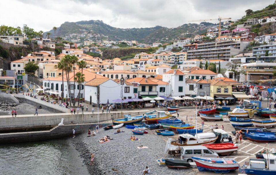 Charming fishing village of Camara de Lobos in Madeira, with vibrant boats along the waterfront and rugged coastline.