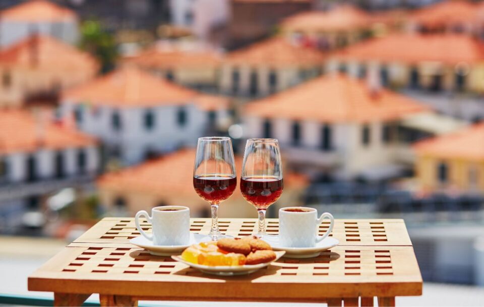Coffee, red wine and biscuits laid out on a wooden table, alfresco, Madeira Island, Portugal.