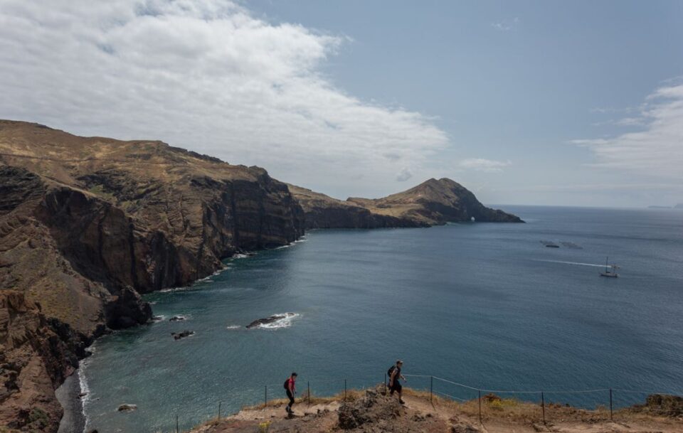 Hikers walking along the trail on San Lourenço Peninsula, Madeira, with rugged cliffs and ocean views.